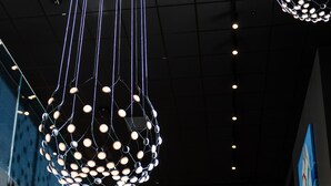 Un interior moderno con una escalera de cristal y lámparas esféricas colgantes.
