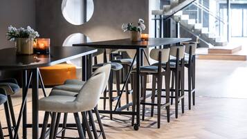 A modern dining area with a long table, multiple chairs, and a small potted plant.