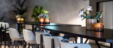 A long dining table with chairs, candles, and a vase of flowers.