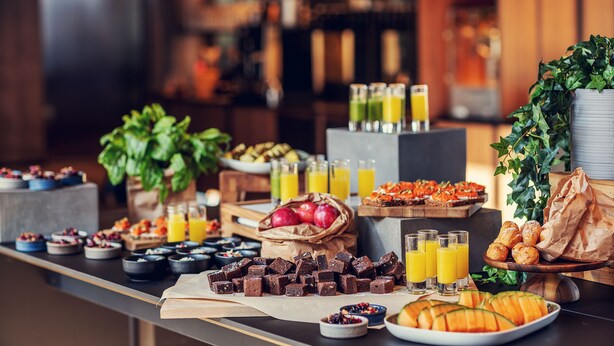 Un bufé con diversas opciones de comida, como frutas, pasteles y bebidas.
