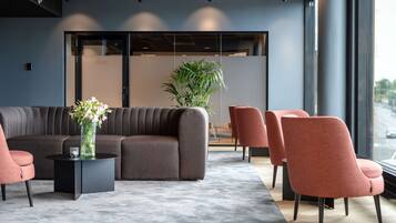 A modern lobby with a grey sofa, a black side table, and a potted plant.