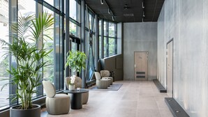Un vestíbulo moderno con grandes ventanales, plantas en macetas y asientos contemporáneos.