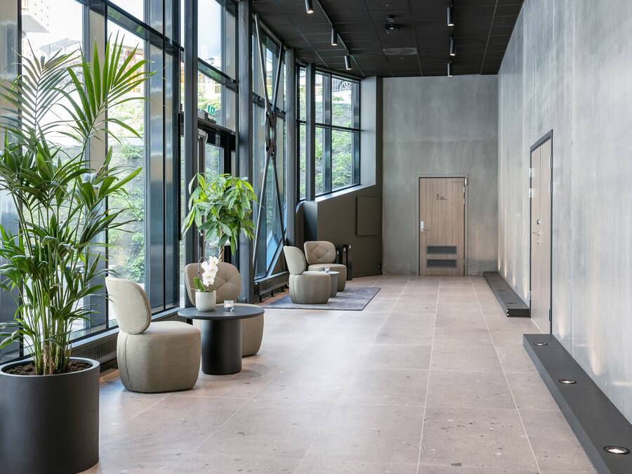 Un hall d’entrée moderne, doté de grandes fenêtres, de plantes en pot et de mobilier contemporain.
