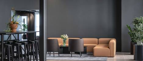 A modern interior with a sofa, chairs, a table, and potted plants.