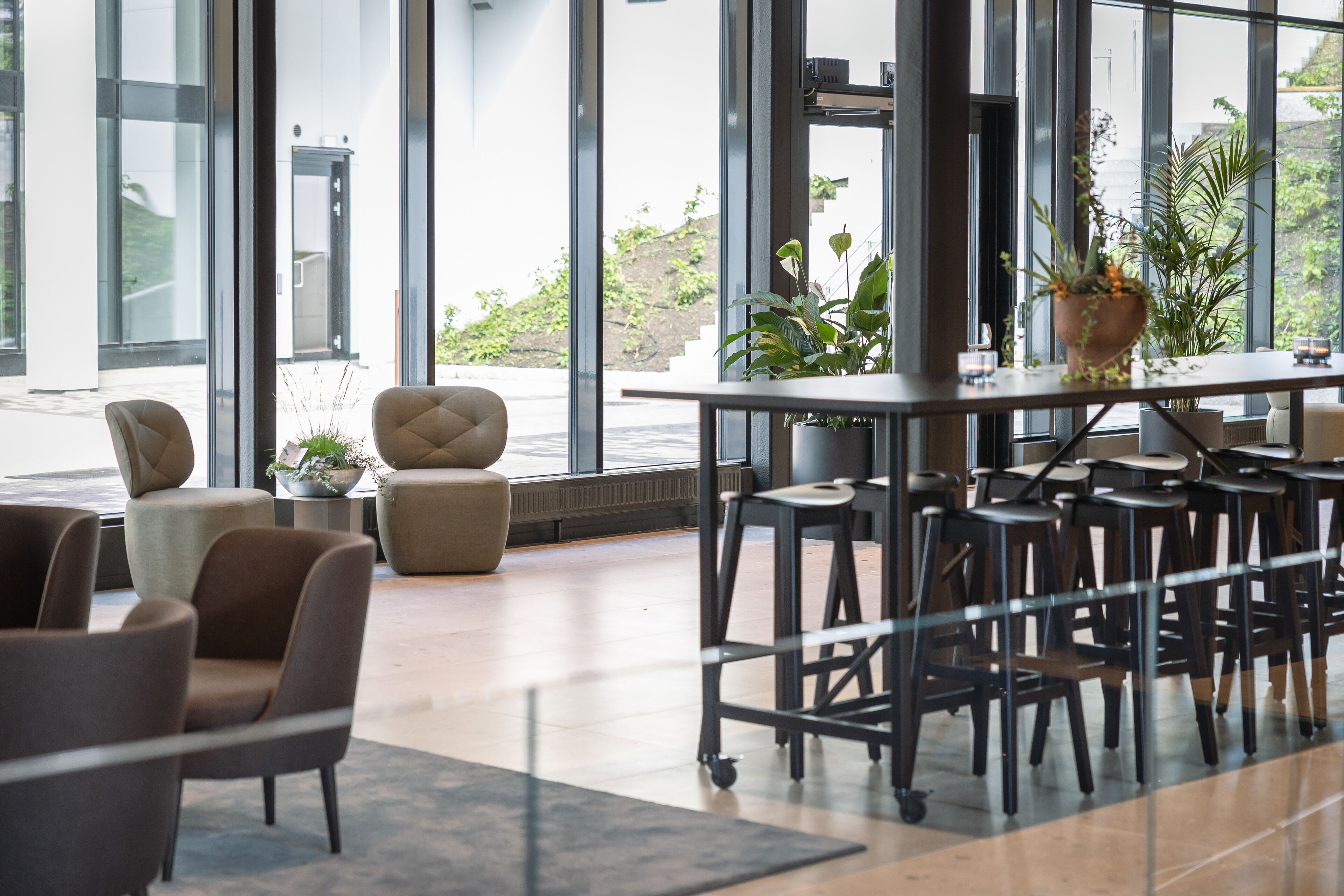 Un interior moderno con amplios ventanales, una zona de bar con taburetes y diferentes disposiciones de asientos.