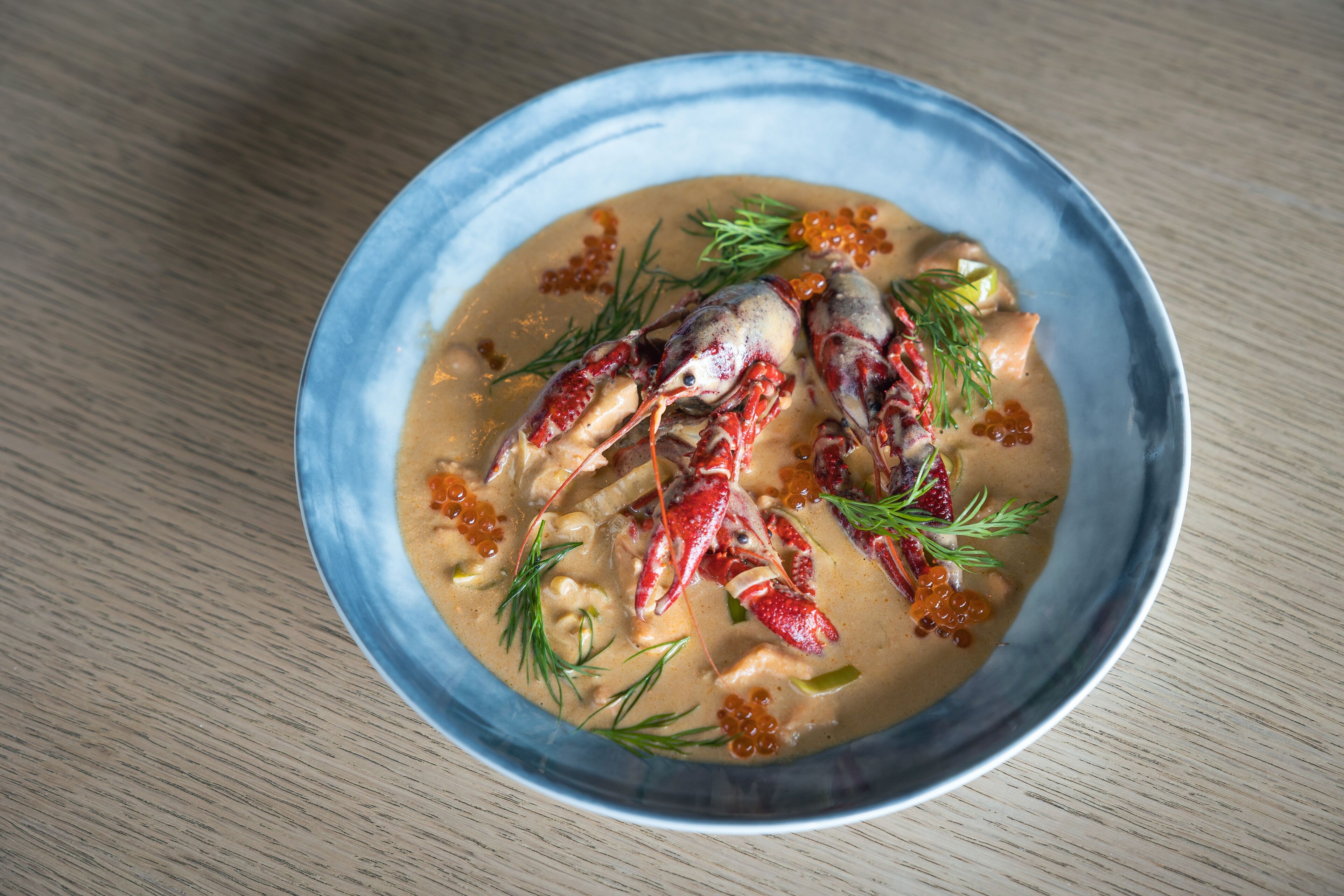Un tazón de sopa de mariscos con langosta y caviar, adornado con eneldo.
