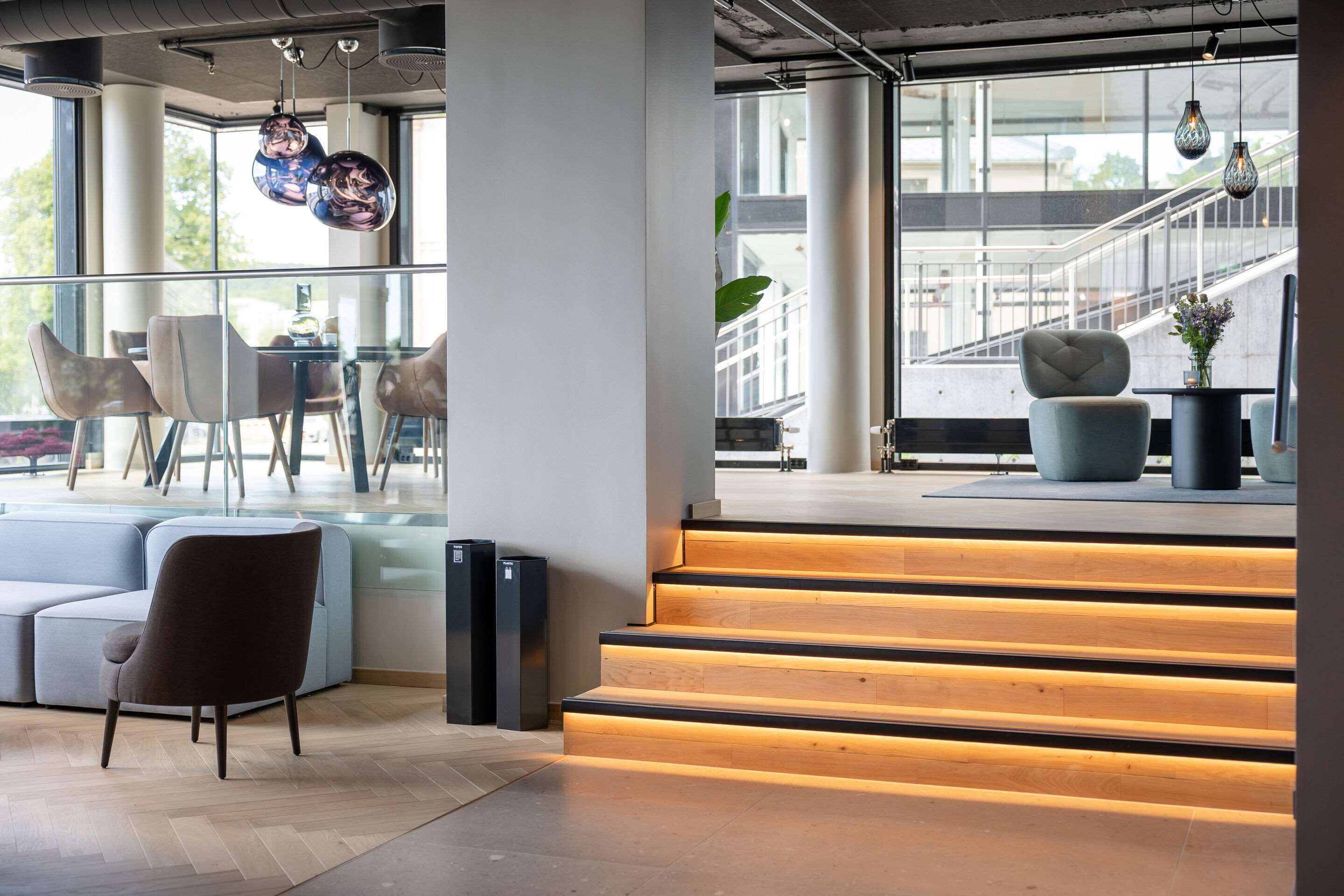 A modern interior with a staircase, seating area, and large windows.