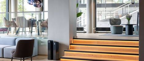 A modern interior with a staircase, seating area, and large windows.