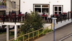 A white building with multiple windows and a balcony with chairs and tables.