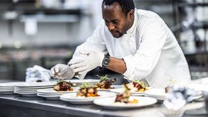A chef in a white uniform preparing dishes on a stainless steel counter. - Straand Hotel (Kviteseid)