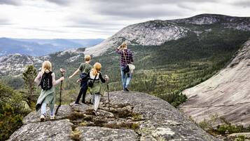 A group of hikers on a rocky mountain peak with a vast forested valley in the background.