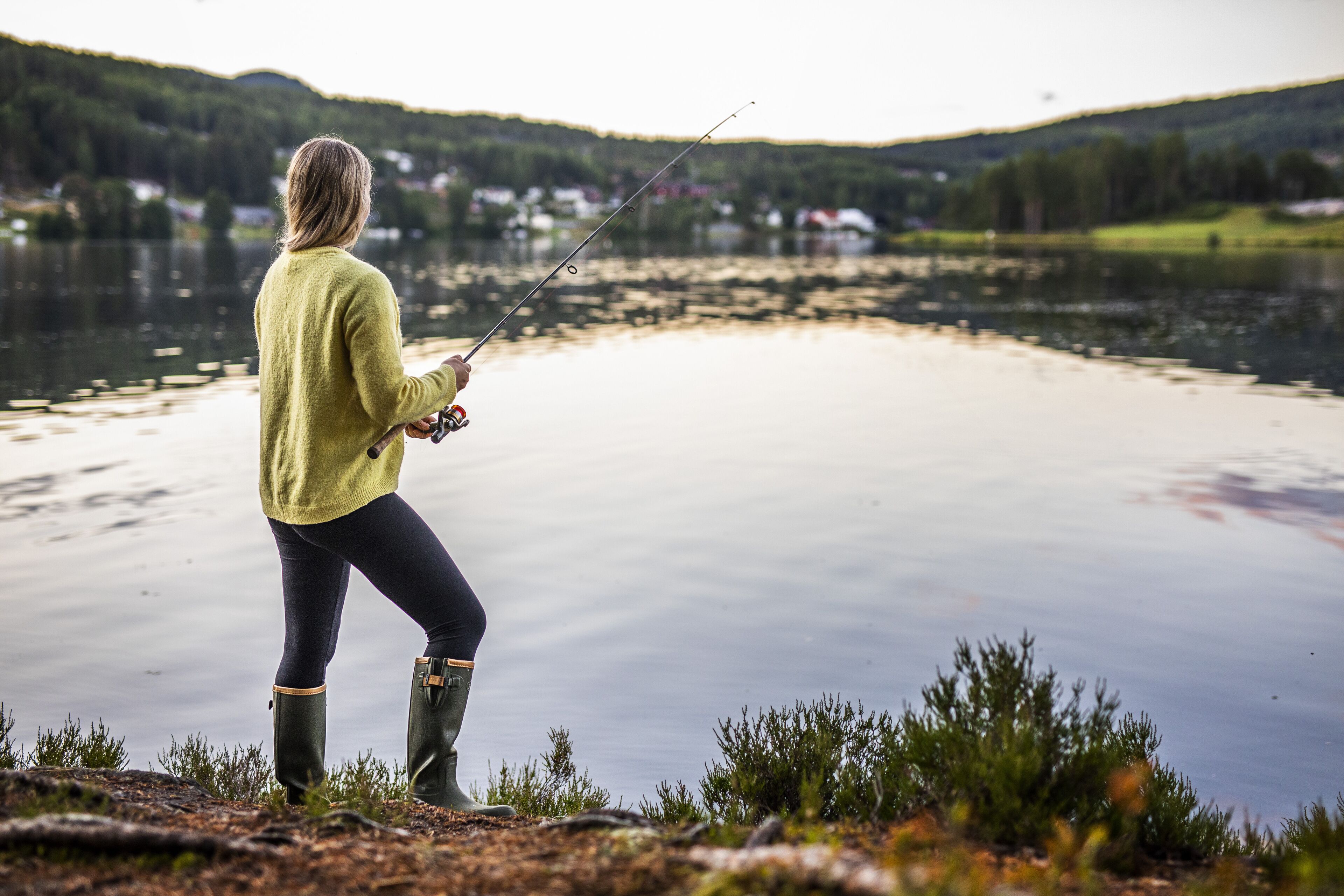 Una persona pescando en un lago tranquilo con vistas despejadas del paisaje circundante.