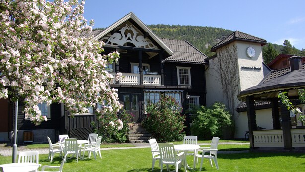 A hotel with a balcony, outdoor seating, and a clock tower. - Straand Hotel (Kviteseid)