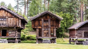 Three rustic log cabins with a central cabin featuring a decorative front door and a small porch. - Straand Hotel (Kviteseid)