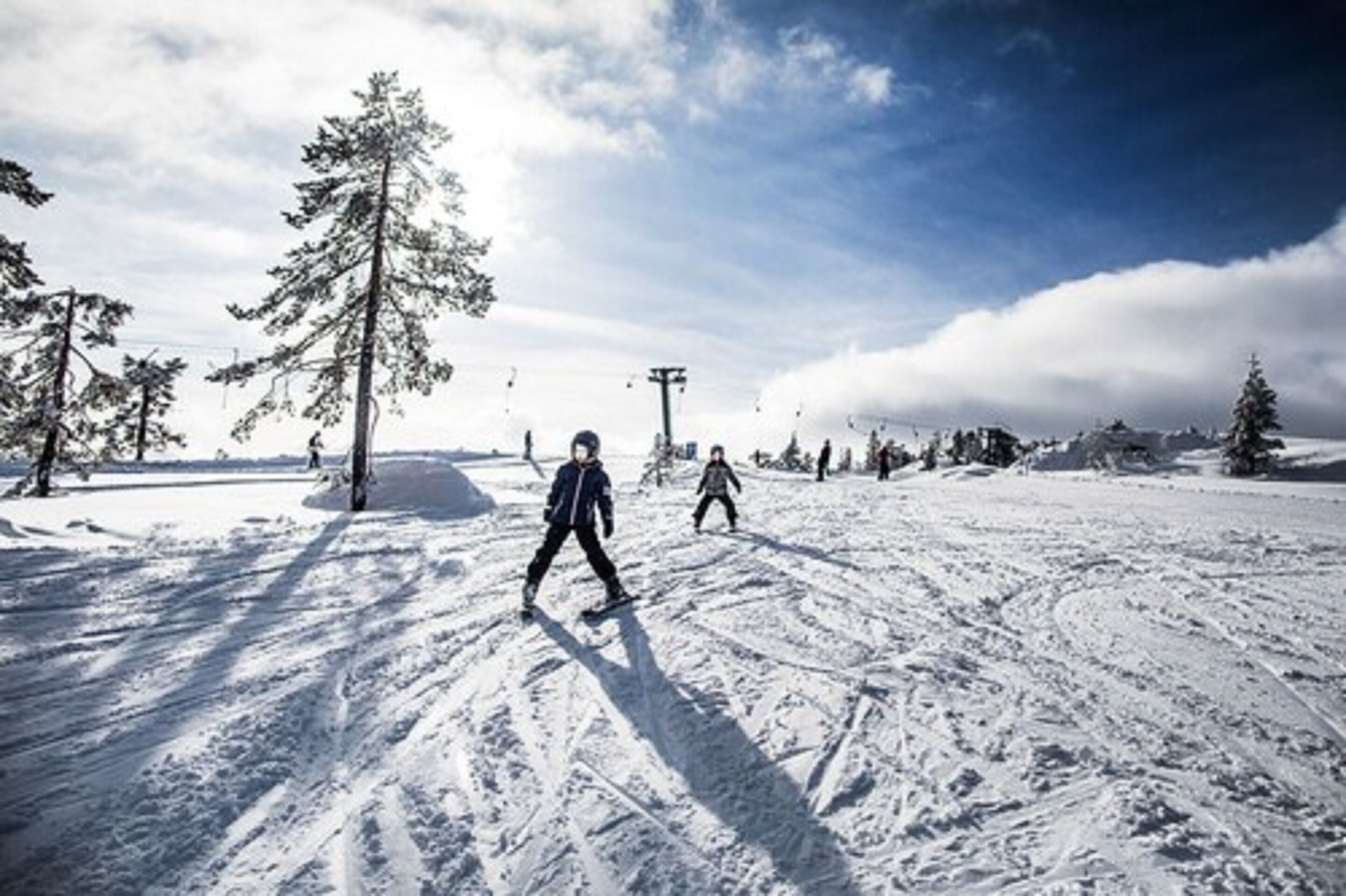 A snowy ski slope with skiers and a clear sky.