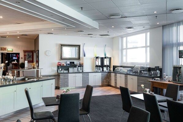 A modern kitchen with a central island, a dining area with chairs, and a large window providing natural light.
