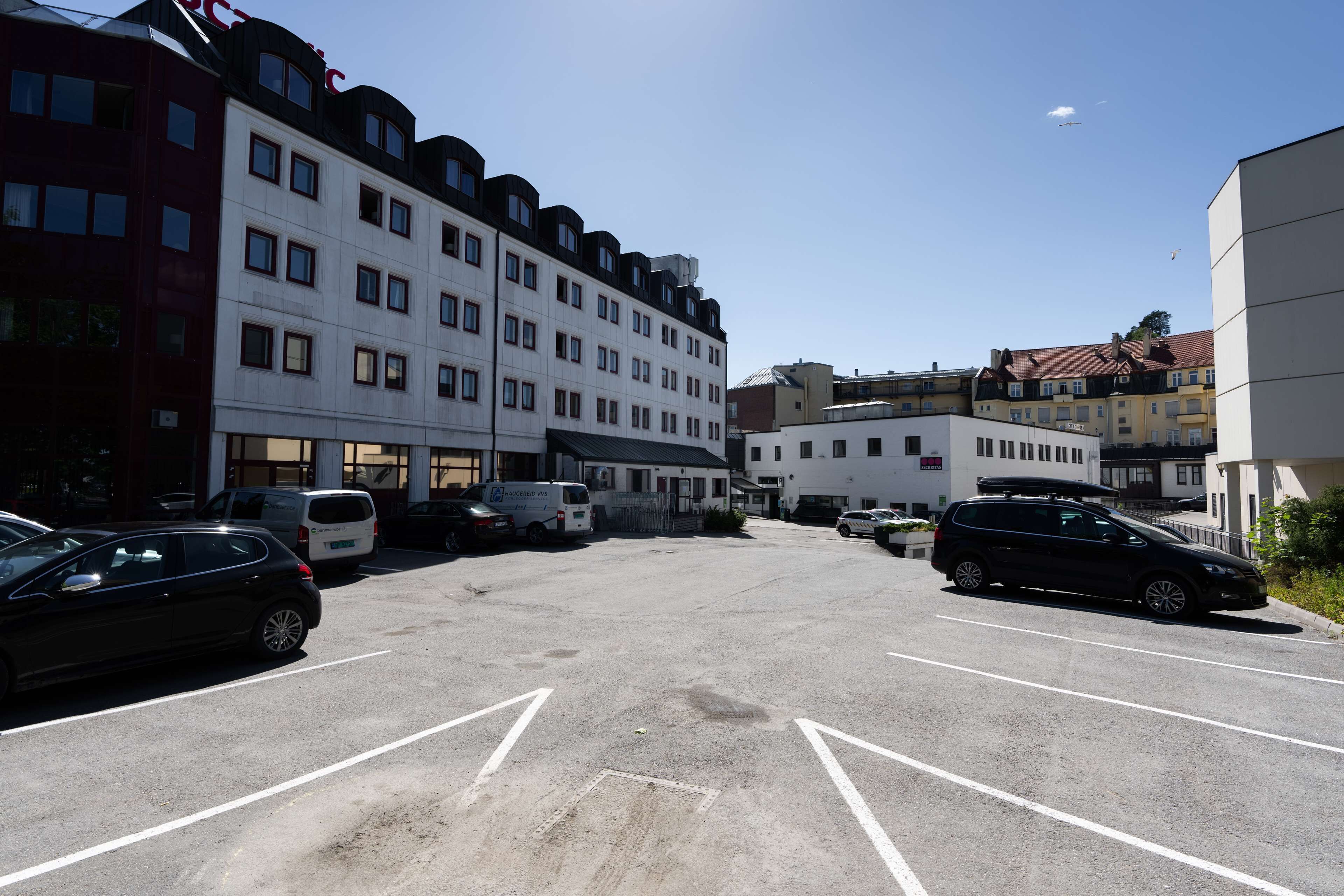 A parking lot with several cars and a white building with multiple windows and balconies.