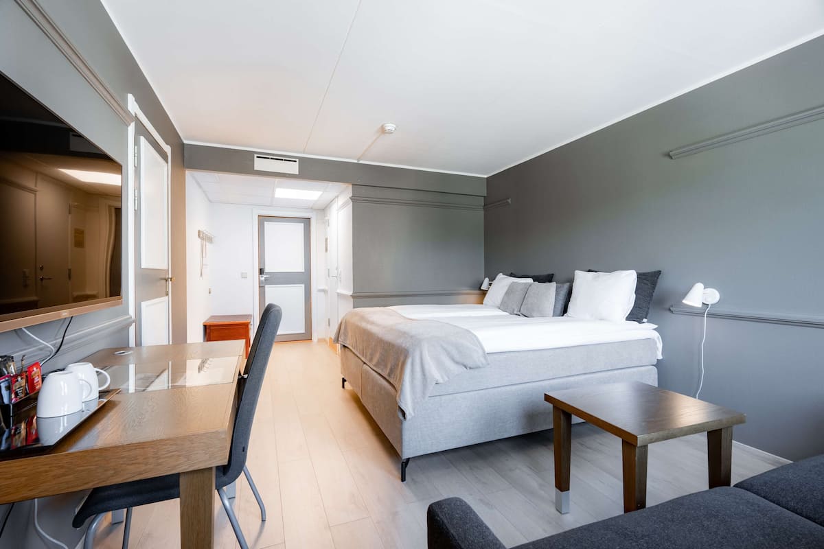 Una habitación de hotel moderna con una cama, un escritorio, una silla y una mesita.