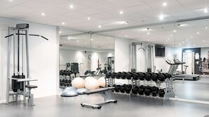 Un gimnasio con equipamiento de ejercicio, estanterías para pesas y pelotas de ejercicio.