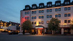 Un hotel con fachada moderna, múltiples ventanas y una entrada destacada.