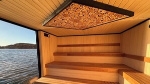A sauna with wooden benches and a sloped ceiling made of logs. - Havna Hotel & Sjøbad (Færder)
