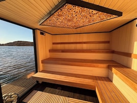 Una sauna con bancos de madera y techo inclinado hecho de troncos.