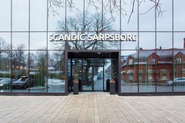 Hotel entrance with a modern glass facade and black pillars.