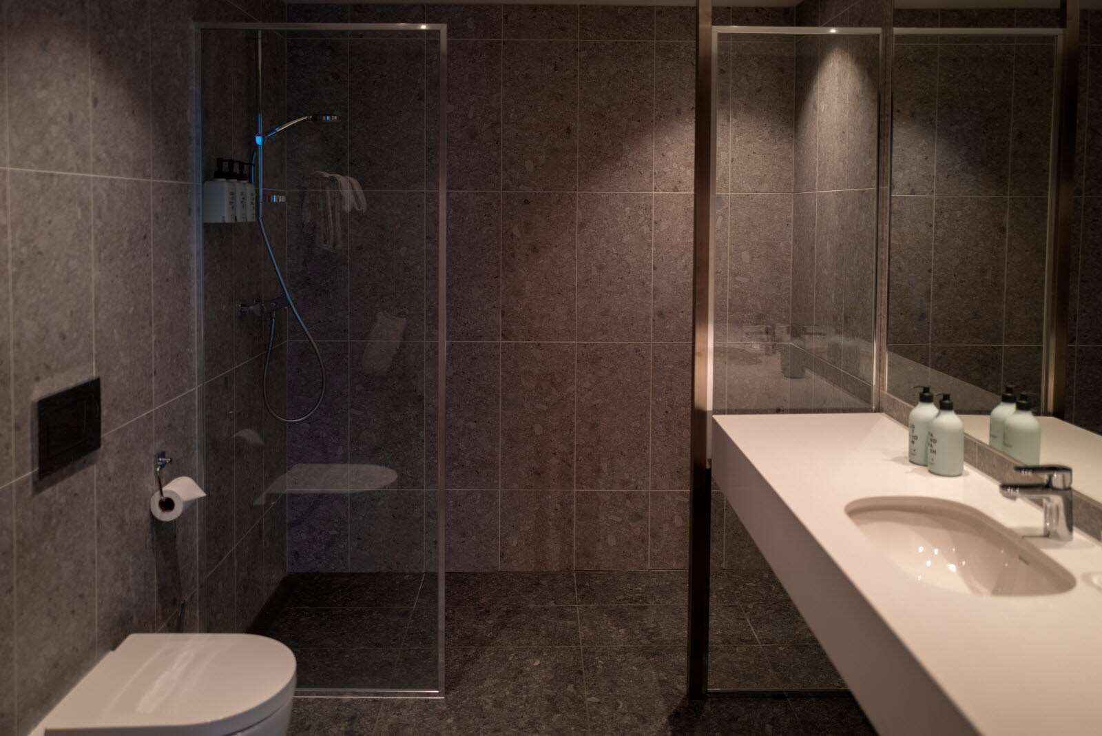 Un baño moderno con ducha de vidrio, lavabo blanco y retrete.