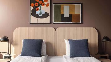 A double bed with two pillows, a wooden headboard, and two bedside tables with lamps.