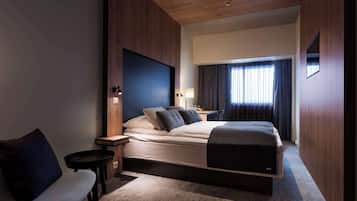 Una habitación de hotel moderna con una cama grande, un escritorio, una silla y un televisor montado en la pared.