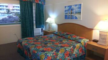 Una habitación de hotel con una cama, una mesita de noche, una lámpara, una ventana con cortinas y un cuadro en la pared.