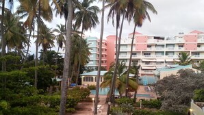 A hotel with multiple floors, a swimming pool, and lush greenery including palm trees. - Villas de Costa Dorada Isabela (Isabela)