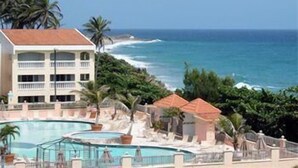 A hotel with a pool, a beach view, and a building with balconies. - Villas de Costa Dorada Isabela (Isabela)