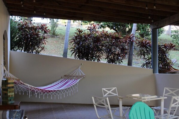 A covered patio area with a hammock, white chairs, and a table. - Fajardo Inn (Fajardo)