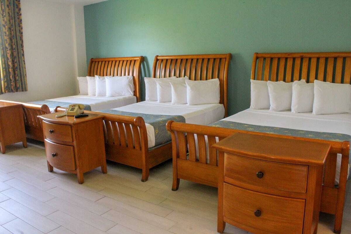 A hotel room with two single beds, a wooden desk, a chair, and a small dresser.
