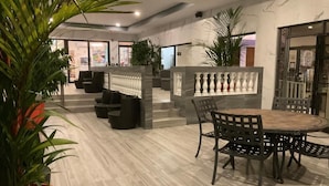 Un espace intérieur moderne avec une table et des chaises en bois, des plantes en pot et un sol en marbre.