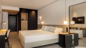 Een moderne hotelkamer met een groot bed, nachtkastjes, een kledingkast, een bureau en een televisie.