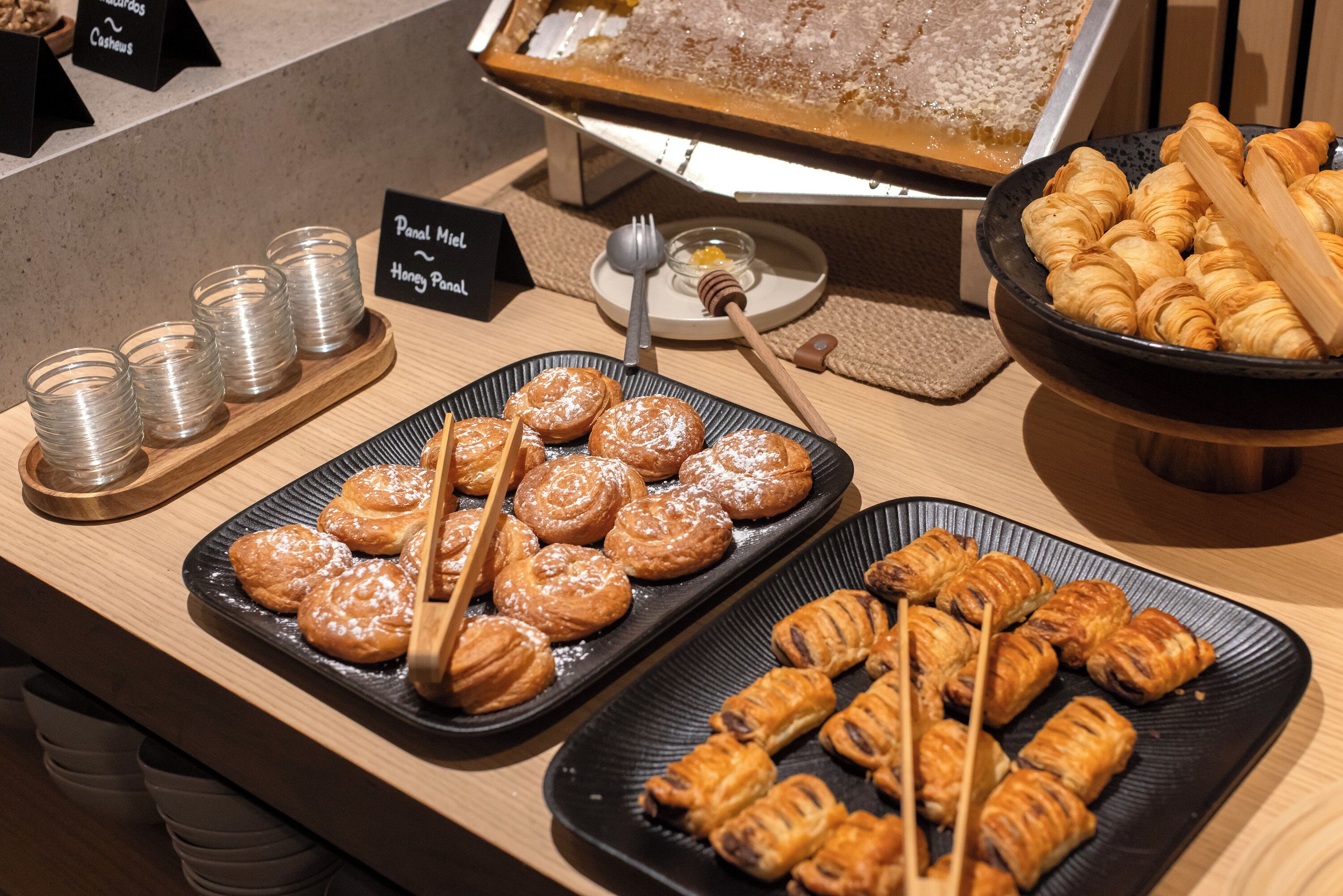 A buffet table with various pastries and a sign indicating the presence of honey and cashews.