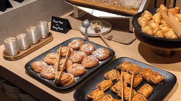Ein Buffet mit verschiedenen Backwaren und einem Schild, das Honig und Cashewnüsse kennzeichnet.