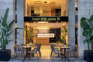 La entrada del Hotel Jaime III con un cartel que dice 'Love the Future', zona de estar al aire libre y diseño moderno.