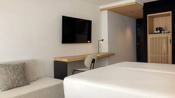 Una habitación de hotel moderna con cama, escritorio con silla, televisor de pantalla plana y armario.