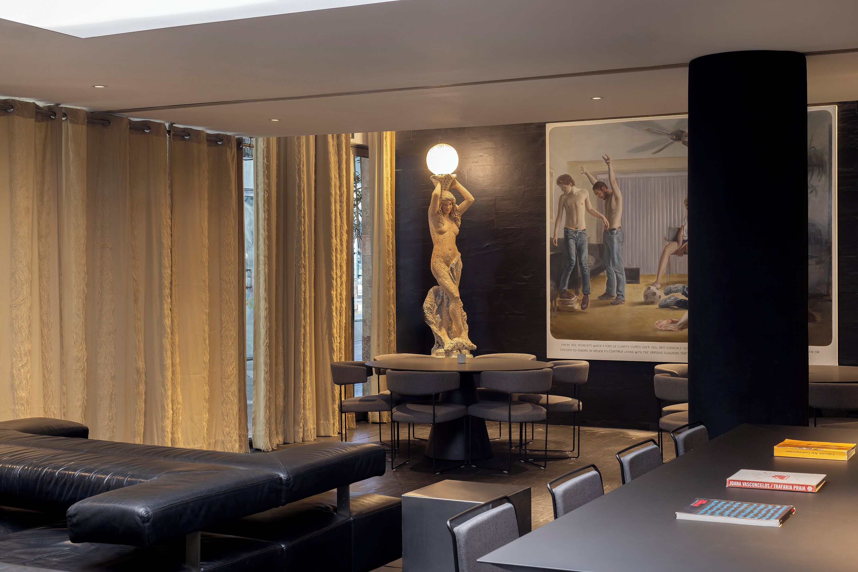 Una habitación de hotel moderna con una cama grande, una mesa de comedor con sillas, una estatua y un cartel en la pared.