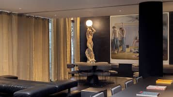 Una habitación de hotel moderna con una cama grande, una mesa de comedor con sillas, una estatua y un cartel en la pared.