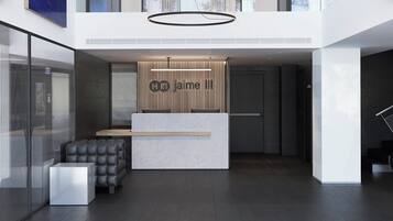 Ein modernes Hotel-Foyer mit minimalistischem Design, ausgestattet mit einer Rezeption, einer Sitzecke und einer Treppe.