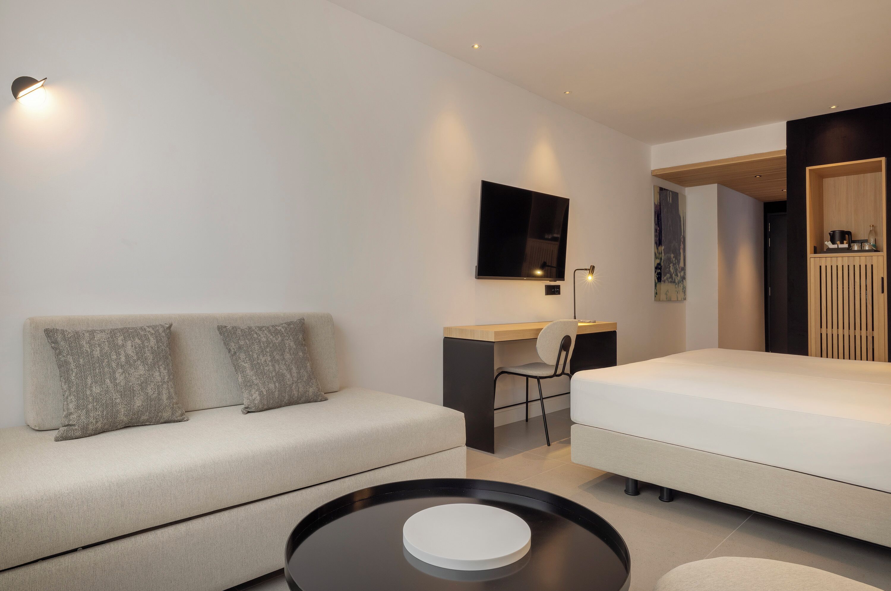 Une chambre d’hôtel moderne équipée d’un canapé, d’un bureau, d’un lit et d’une table ronde.