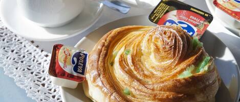 A breakfast setting with a croissant, a glass of orange juice, a cup, and a plate with butter.