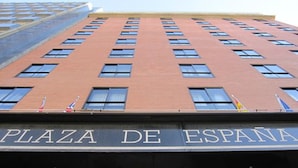A tall brick building with a sign reading "PLAZA DE ESPAÑA" at the top.