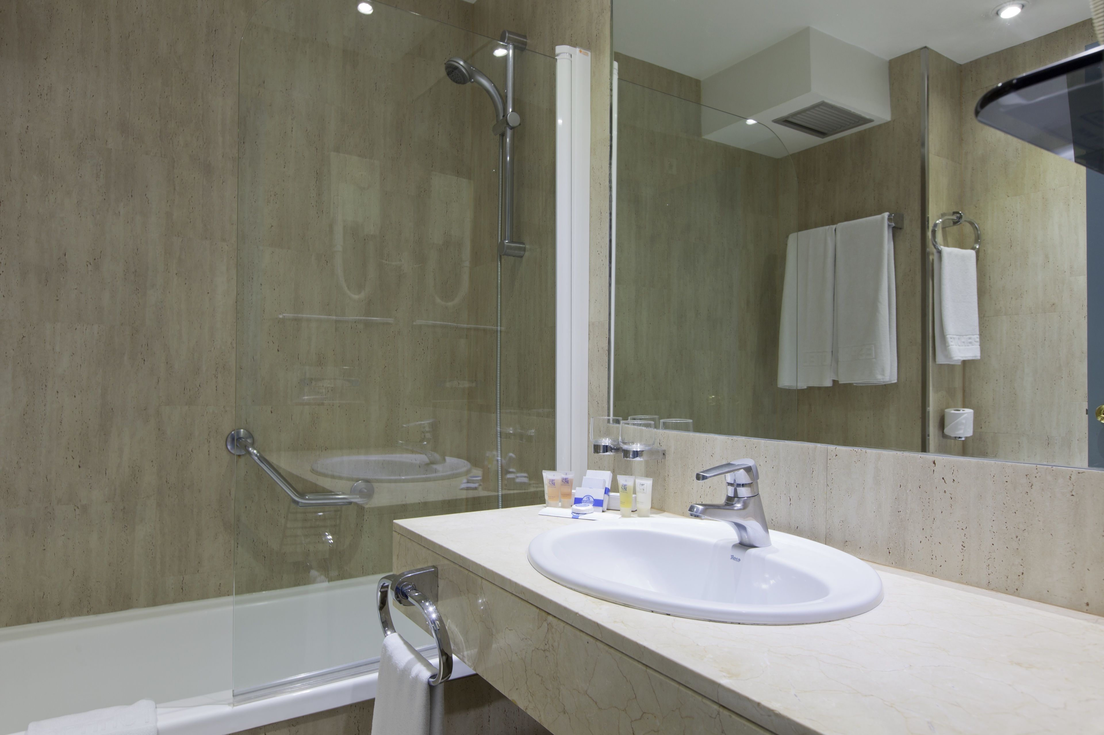 A modern bathroom with a glass-enclosed shower, a sink, and a large mirror.