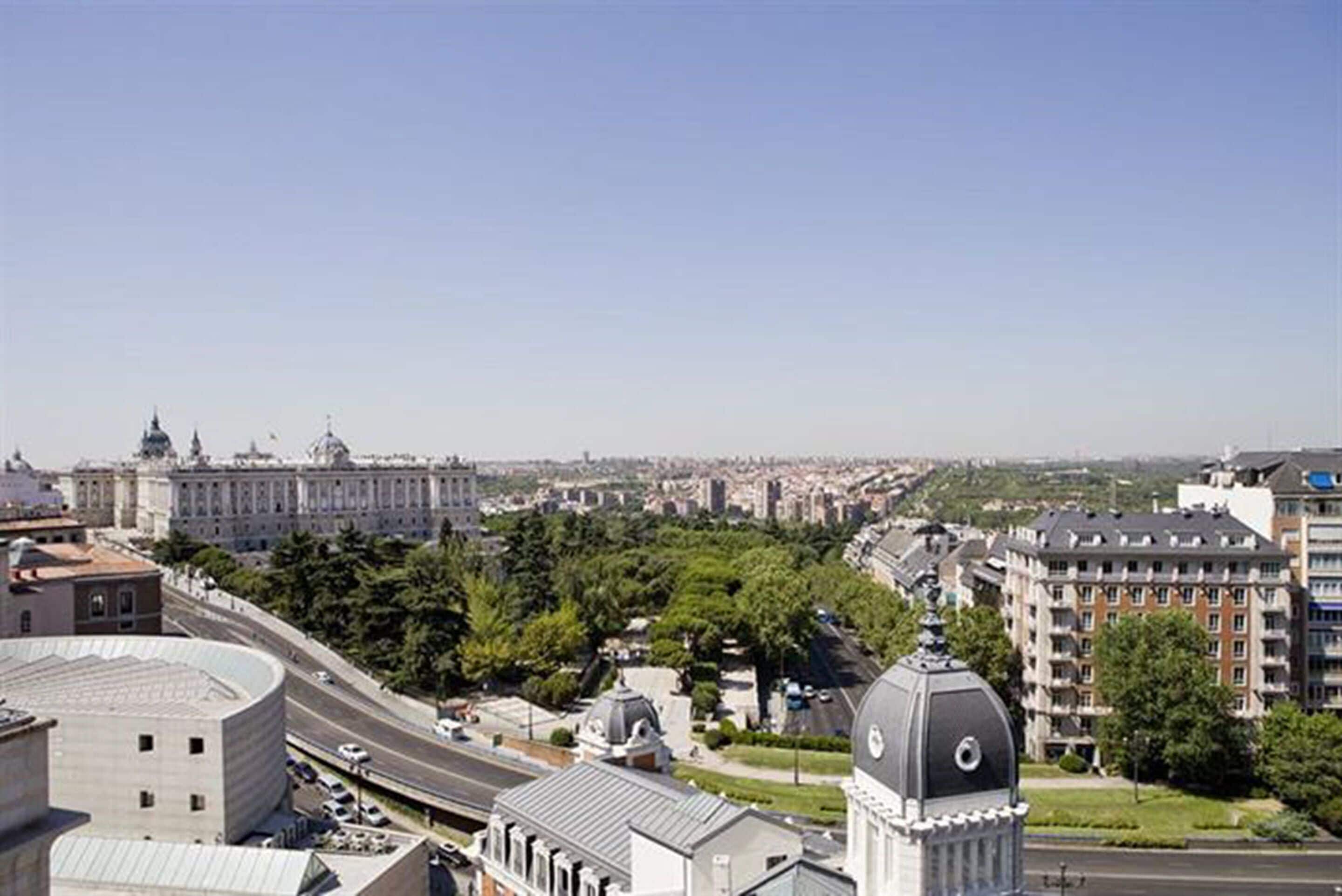 Un paisaje urbano con un edificio destacado que presenta una cúpula y una estructura curva grande.