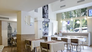 A restaurant with multiple tables and chairs, a bar area, and large windows with a view of the outside.
